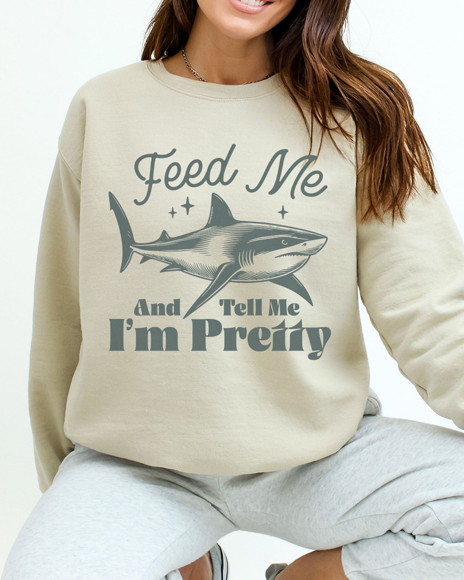 Model wearing sand color sweatshirt with 'Feed Me And Tell Me I'm Pretty' graphic design - close-up