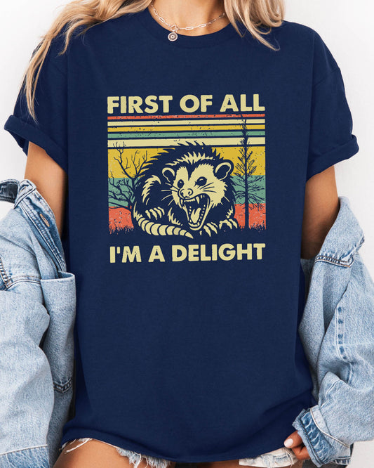 Woman wearing retro opossum graphic shirt in navy blue color with the funny quote "first of all, I'm a delight"