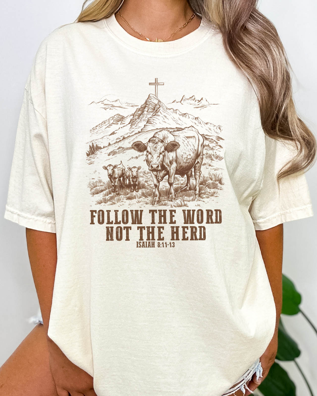 Woman wearing natural beige Christian graphic shirt with Bible verse quote 'Follow the Word, Not the Herd.