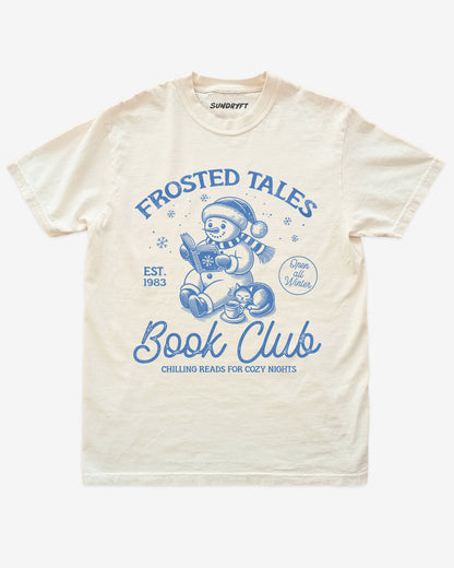 Ivory shirt with cute snowman reading book design and “Frosted Tales Book Club” text