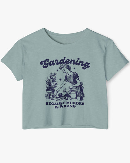 Flat-lay of a stonewash green crop top featuring a funny retro-style graphic of a housewife gardening with the text ‘Gardening, Because Murder Is Wrong’.