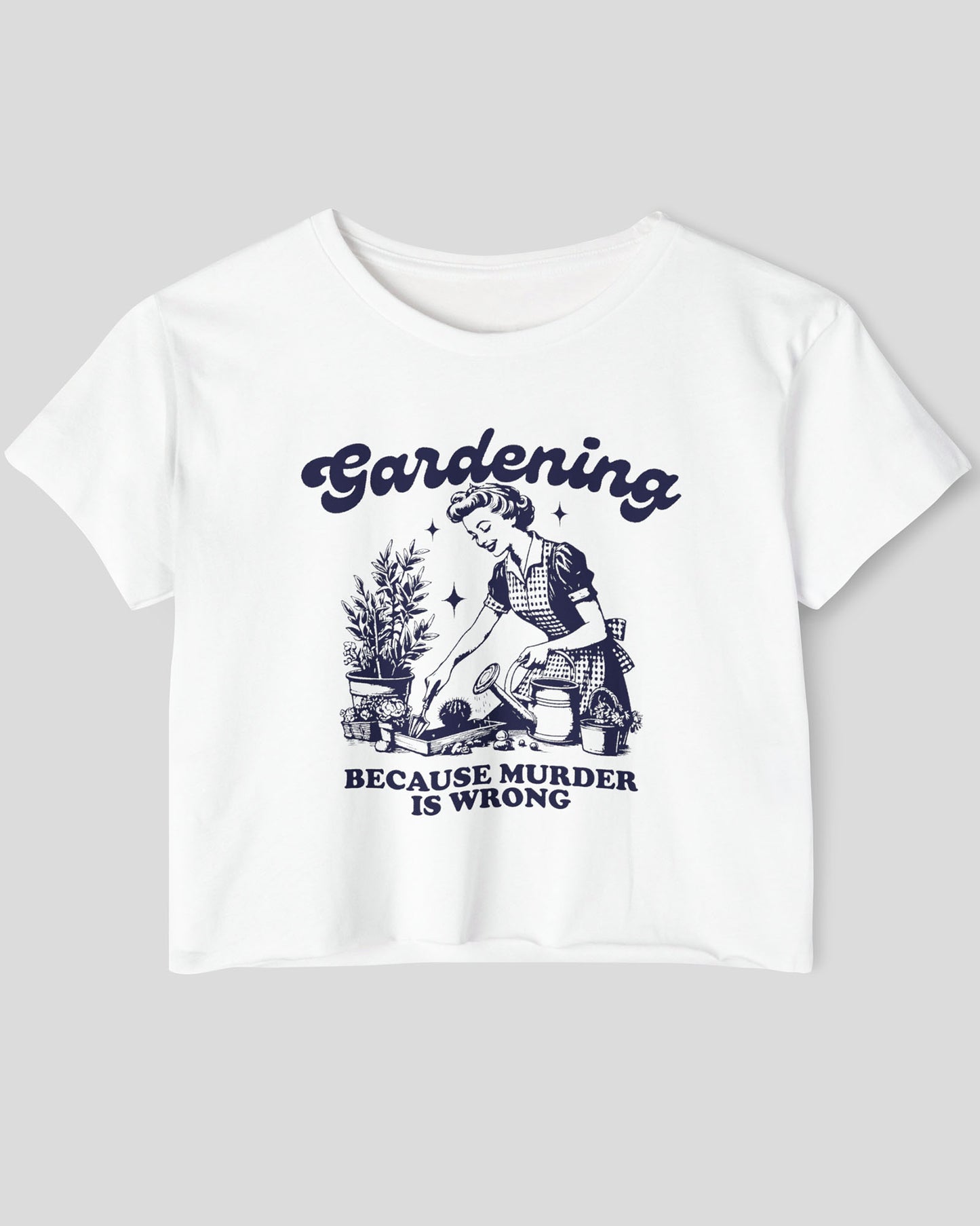 Flat-lay of a white crop top featuring a funny retro-style graphic of a housewife gardening with the text ‘Gardening, Because Murder Is Wrong’.