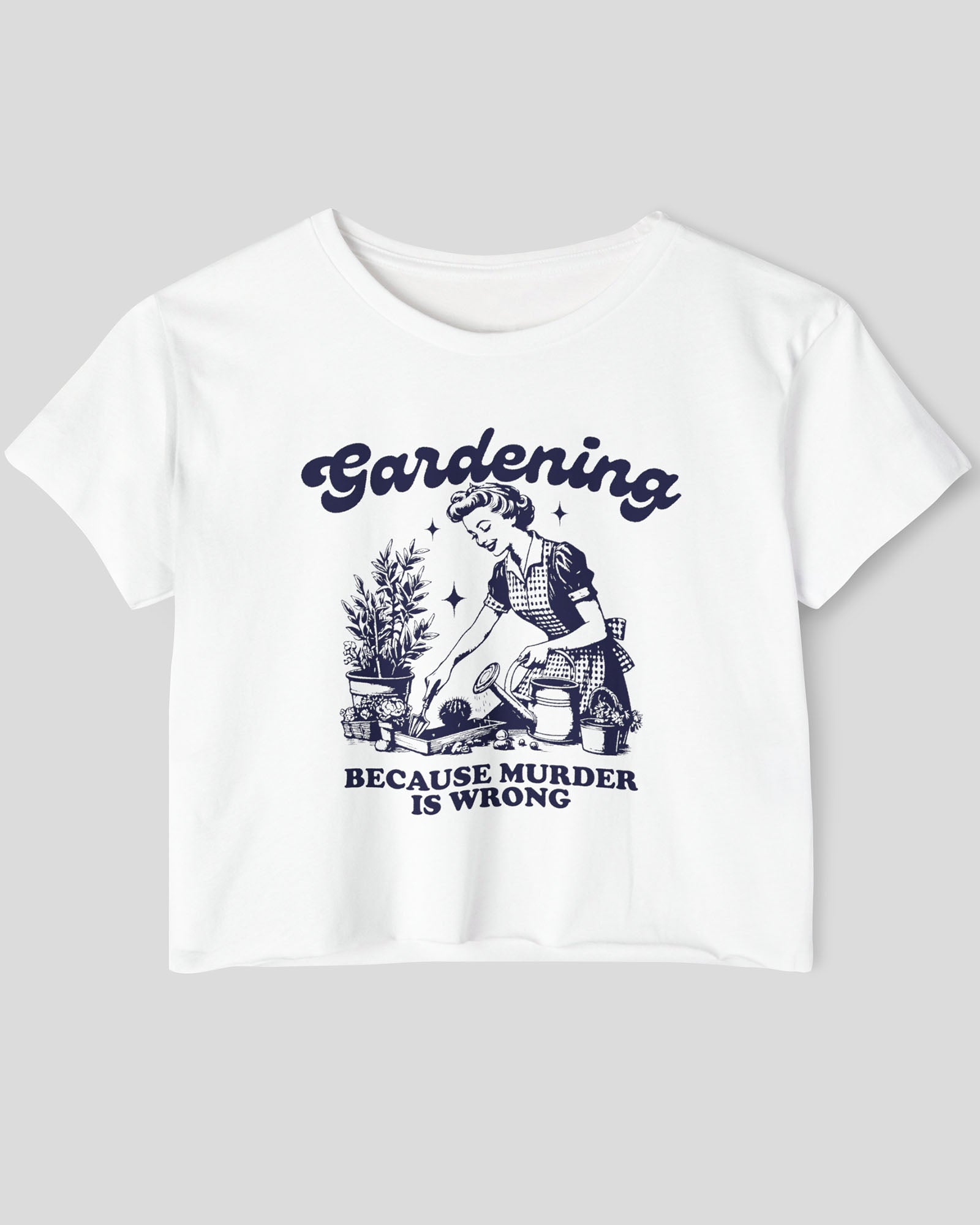 Flat-lay of a white crop top featuring a funny retro-style graphic of a housewife gardening with the text ‘Gardening, Because Murder Is Wrong’.
