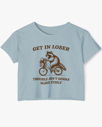 Flat lay stonewash denim 'Get In Loser, Trouble Ain't Gonna Make Itself' crop top featuring a funny retro raccoon riding a bicycle.