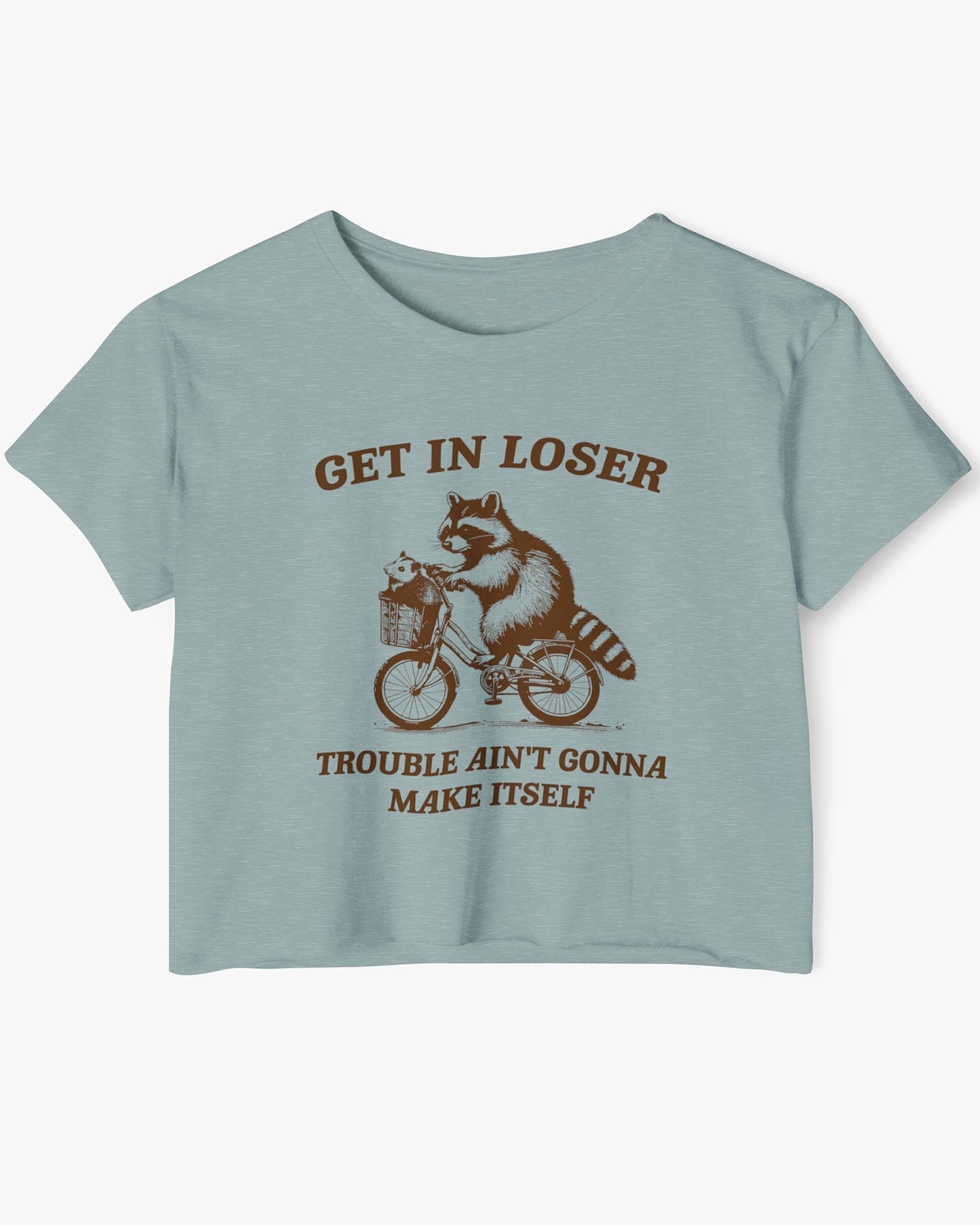 Flat lay stonewash green 'Get In Loser, Trouble Ain't Gonna Make Itself' crop top featuring a funny retro raccoon riding a bicycle.