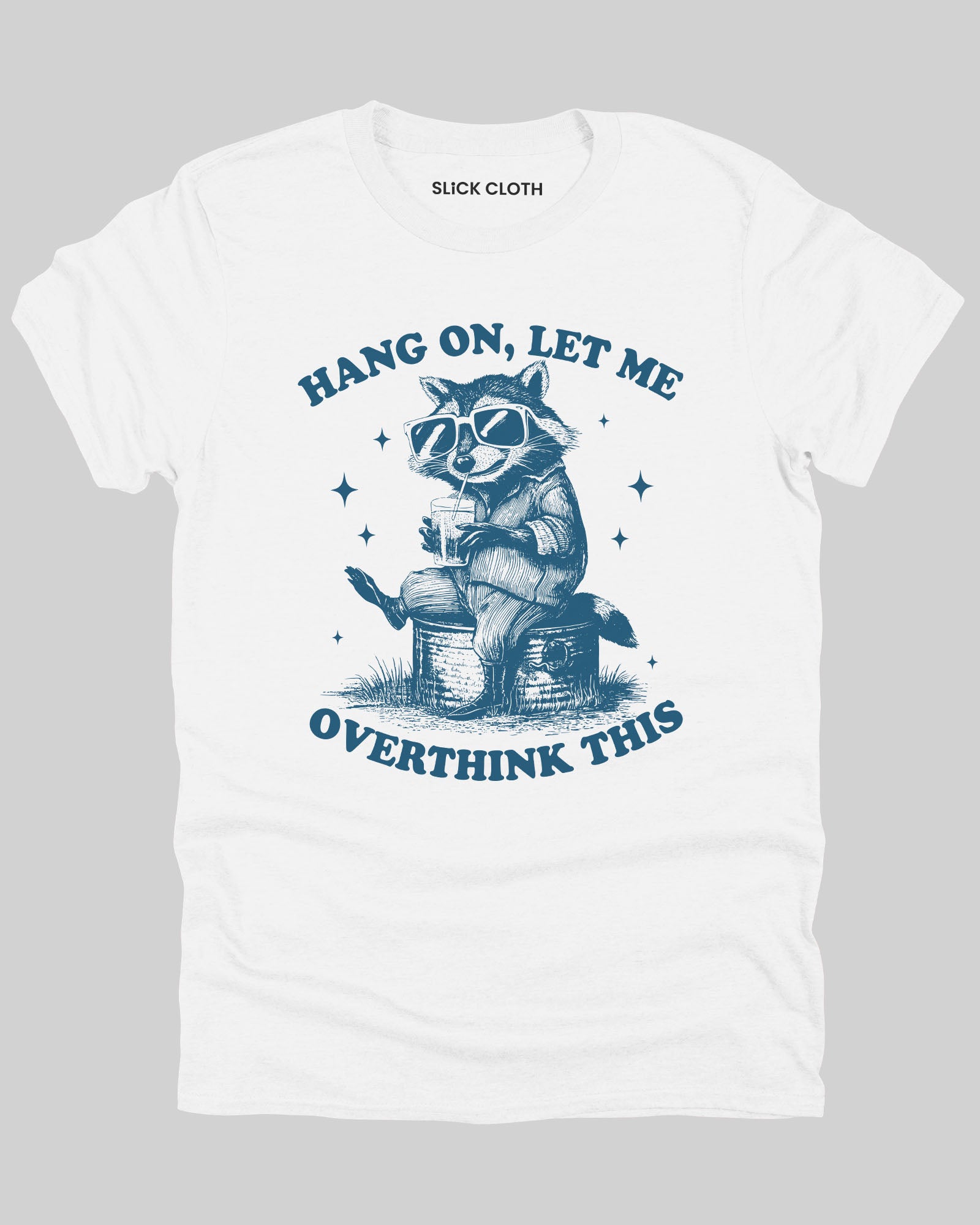 White flat lay 'Hang On Let me Overthink This' shirt with funny retro raccoon wearing sunglasses graphic.