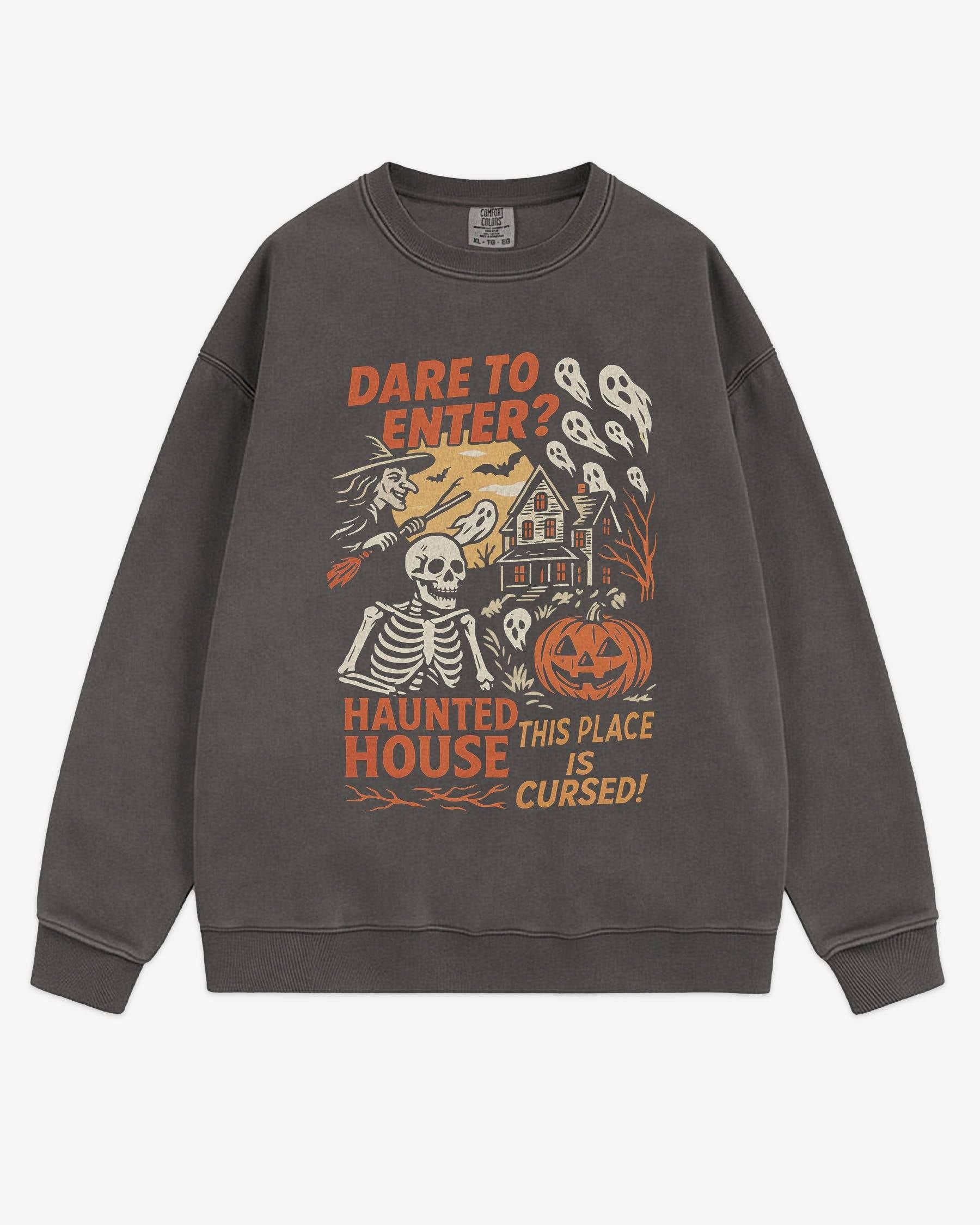 Flat lay pepper Halloween sweatshirt reading ‘Dare To Enter – Haunted House’ with retro graphic of haunted house, skeletons, and a witch.
