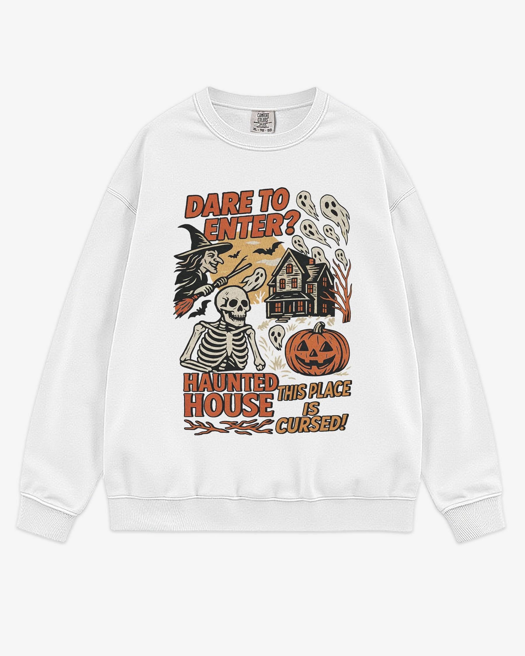 Flat lay white Halloween sweatshirt reading ‘Dare To Enter – Haunted House’ with retro graphic of haunted house, skeletons, and a witch.