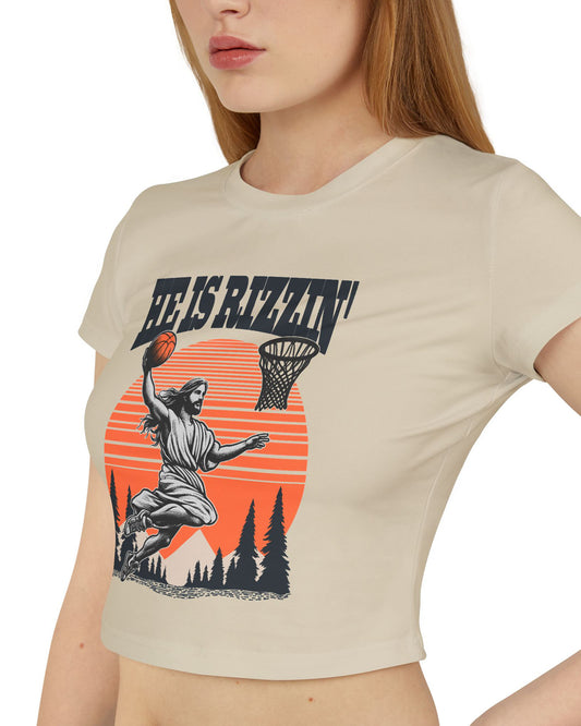 Woman wearing a sand 'He Is Rizzin' baby tee featuring a funny retro Jesus playing basketball graphic, perfect for Y2K and Christian humor style.