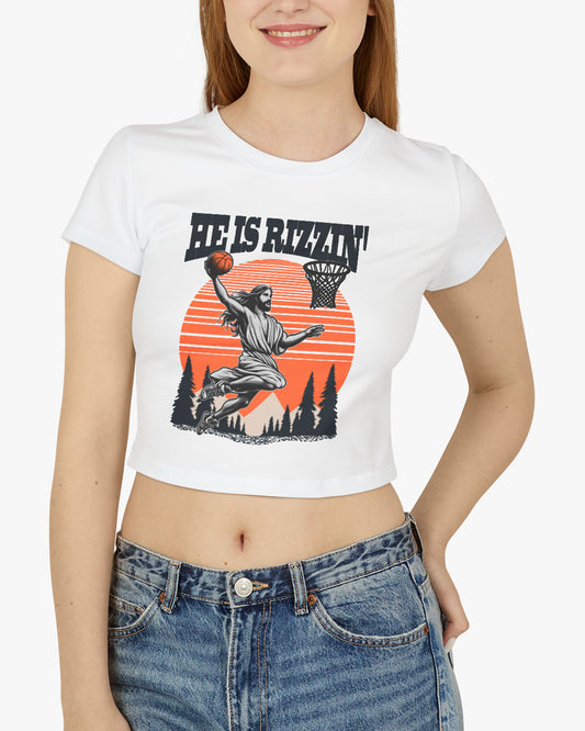 Woman wearing a white 'He Is Rizzin' baby tee featuring a funny retro Jesus playing basketball graphic, perfect for Y2K and Christian humor style.

