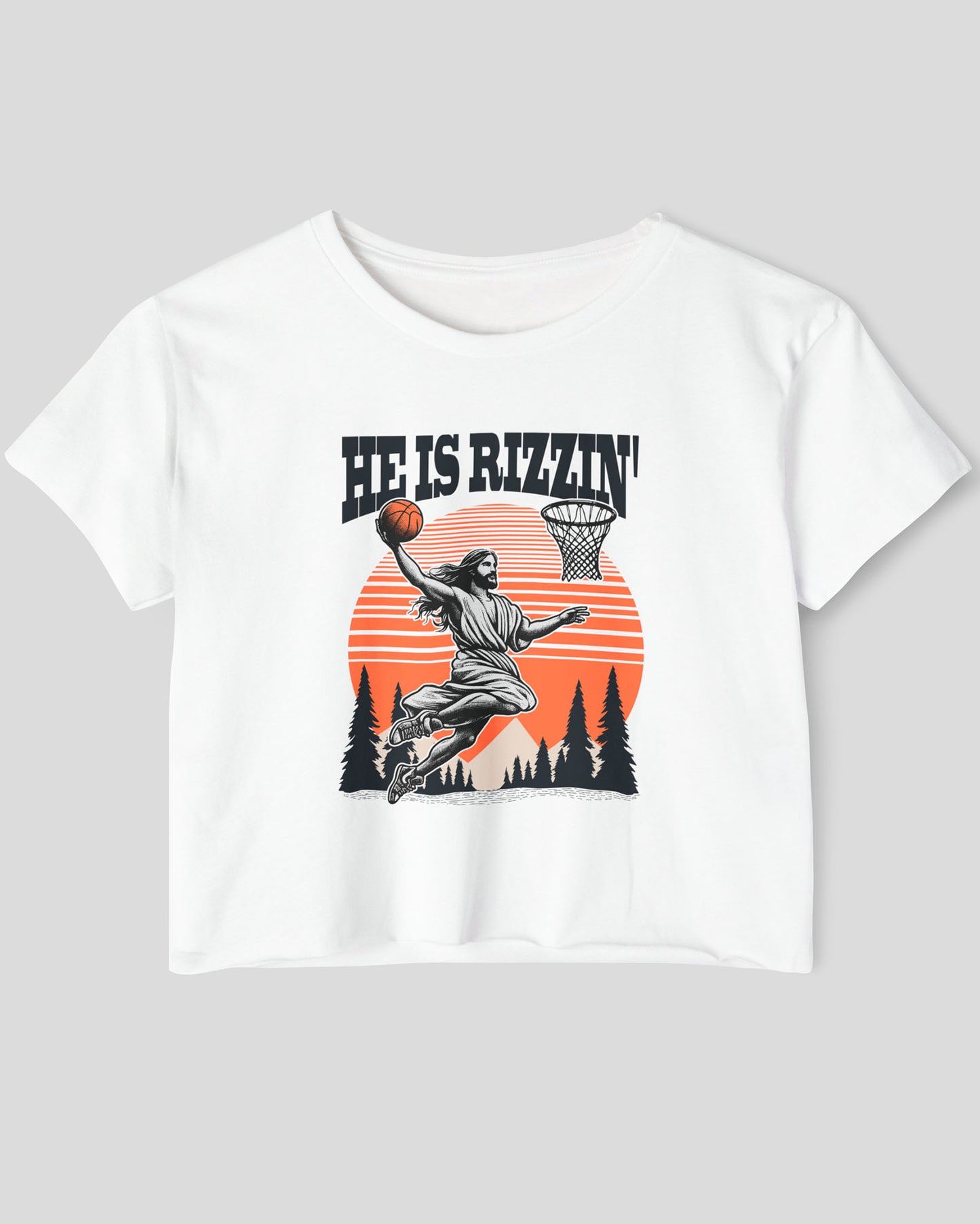 Flat lay of a white 'He Is Rizzin' crop top featuring a funny retro graphic of Jesus slam-dunking a basketball.