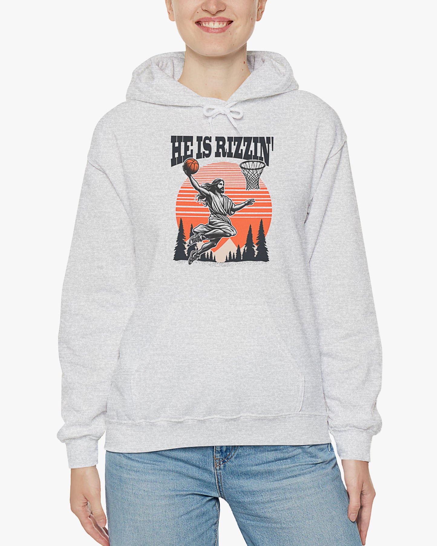 Woman wearing ash gray 'He Is Rizzin' hoodie featuring retro Jesus dunking basketball graphic, ideal for Easter.