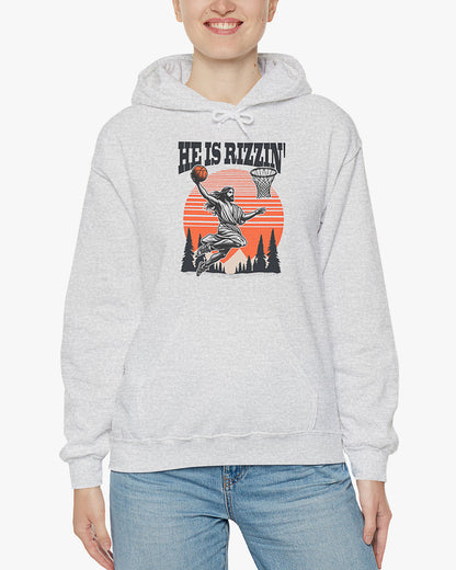 Woman wearing ash gray 'He Is Rizzin' hoodie featuring retro Jesus dunking basketball graphic, ideal for Easter.