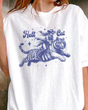 Close-up of woman wearing a white "Hell Cat" shirt with a retro graphic of a cowgirl riding a tiger.