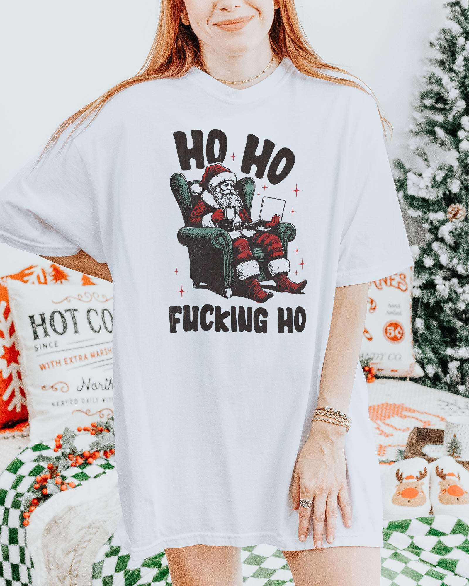 Woman wearing a white "Ho Ho Fucking Ho" shirt with a funny retro graphic of Santa Claus sitting in an armchair.