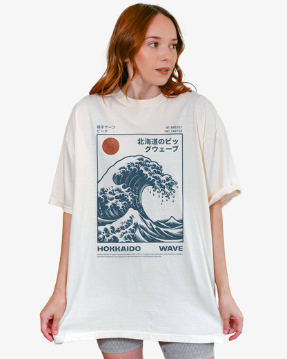 Woman wearing an ivory ‘Hokkaido Wave’ surf shirt with a retro Japanese great wave graphic in traditional ukiyo-e style.