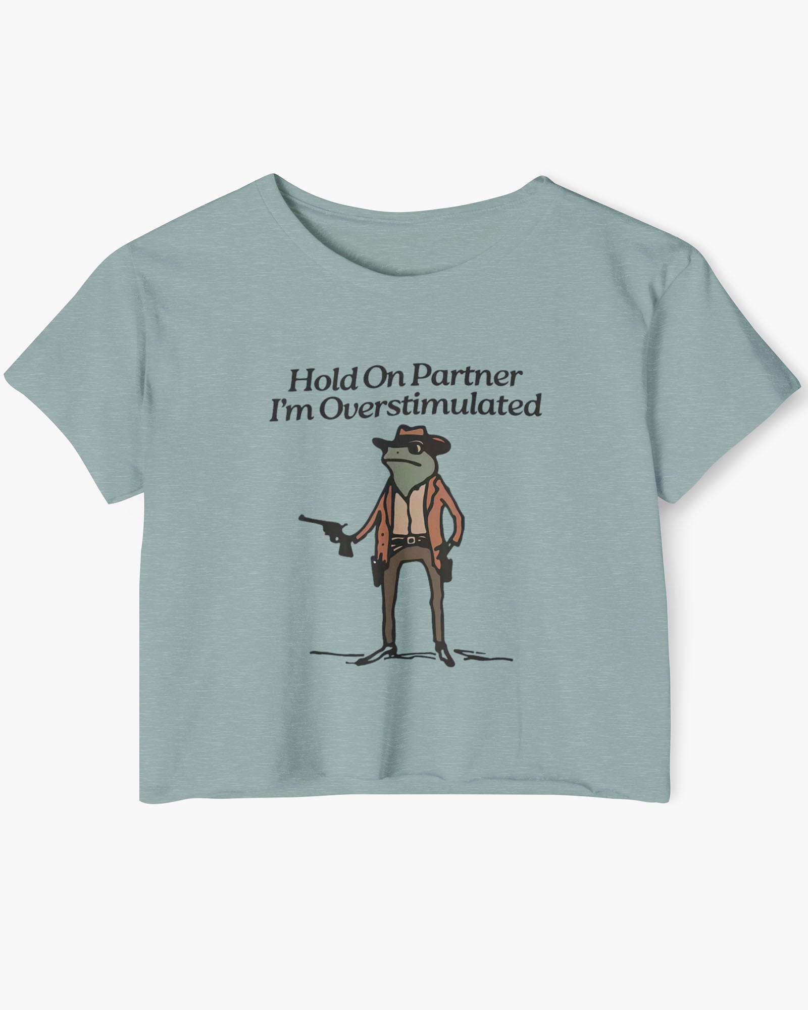 Flat lay stonewash green 'Hold On Partner, I'm Overstimulated' crop top featuring a funny retro cowboy frog graphic.