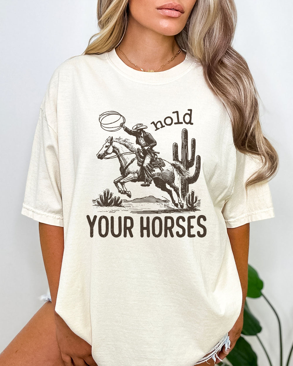 Woman wearing ivory color shirt with 'Hold Your Horses' graphic design