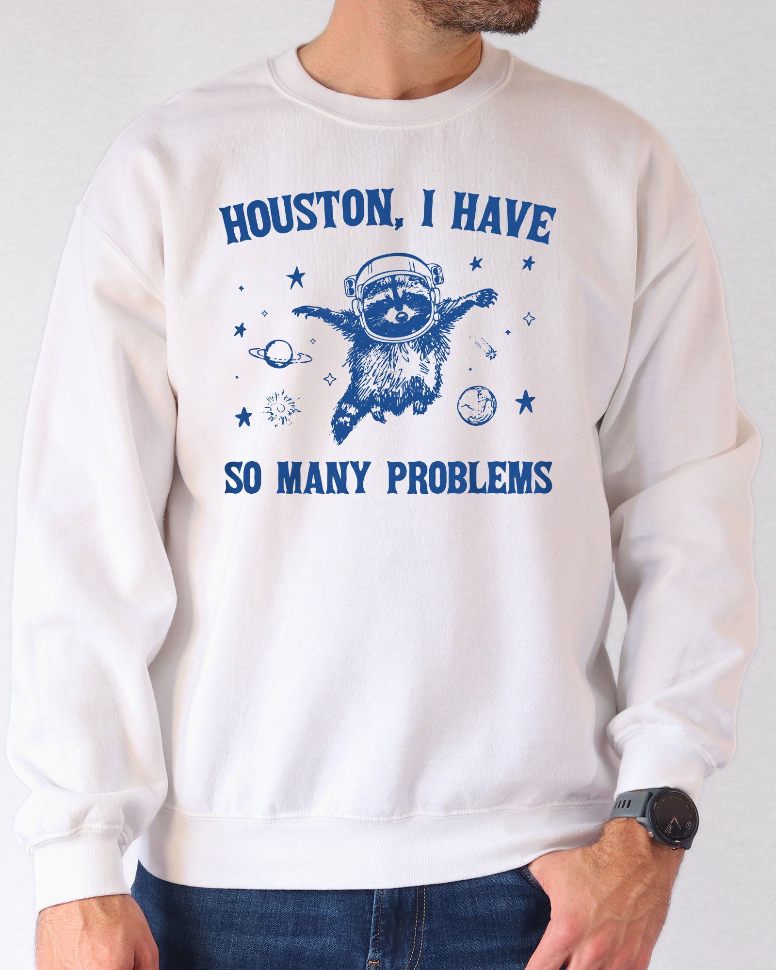 Man wearing a white sweatshirt featuring a funny retro astronaut raccoon graphic and the quote 'Houston I Have So Many Problems'.
