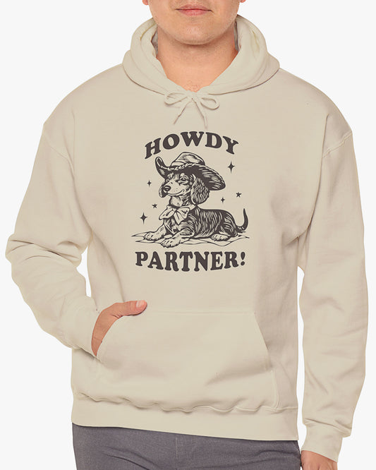 Man wearing sand beige 'Howdy Partner' hoodie with funny retro cowboy dachshund graphic