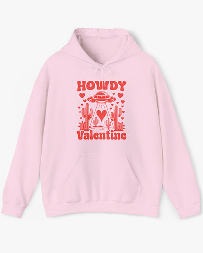 Flat lay light pink Howdy Valentine hoodie featuring a retro western desert scene with a UFO and floating hearts graphic.