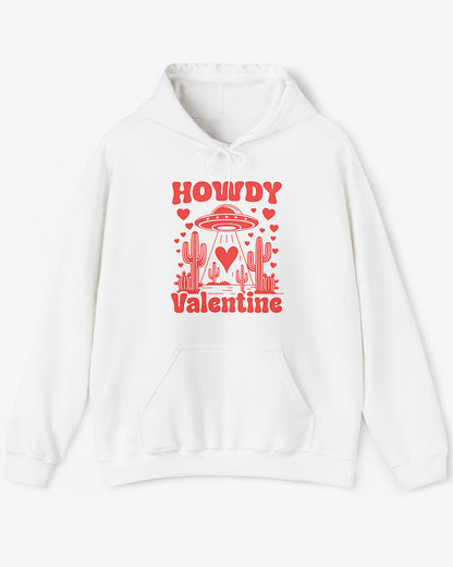 Flat lay white Howdy Valentine hoodie featuring a retro western desert scene with a UFO and floating hearts graphic.
