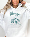 Woman wearing a white hoodie with a cute, funny retro bear pushing a shopping cart and the quote 'I Got 99 Problems But A Sweet Little Treat Is Solving Most Of Them'.