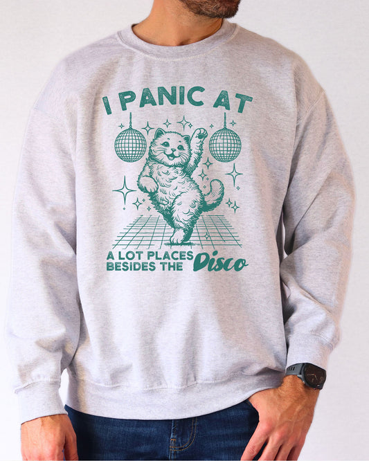 Man wearing an ash gray sweatshirt featuring a funny retro disco cat graphic and the quote 'I Panic At A Lot Of Places Besides The Disco'.