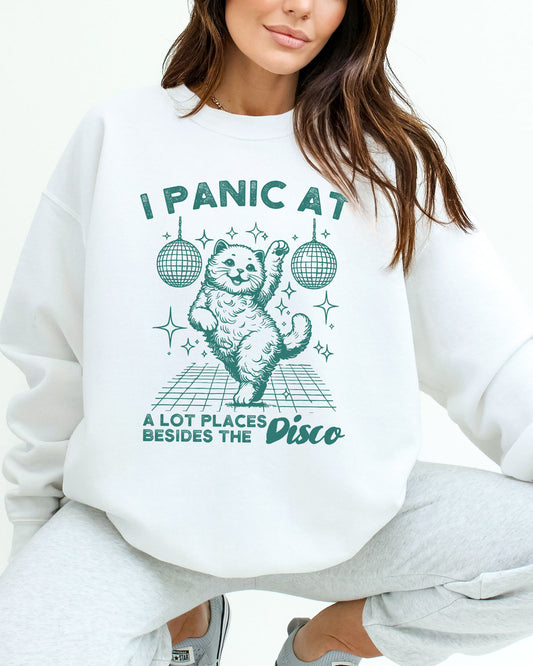 Woman wearing a white sweatshirt featuring a funny retro disco cat graphic and the quote 'I Panic At A Lot Of Places Besides The Disco'.