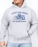 Man wearing an ash gray hoodie featuring a funny retro-style raccoon gang graphic and the quote 'I Put The Sexy In Dyslexia'.