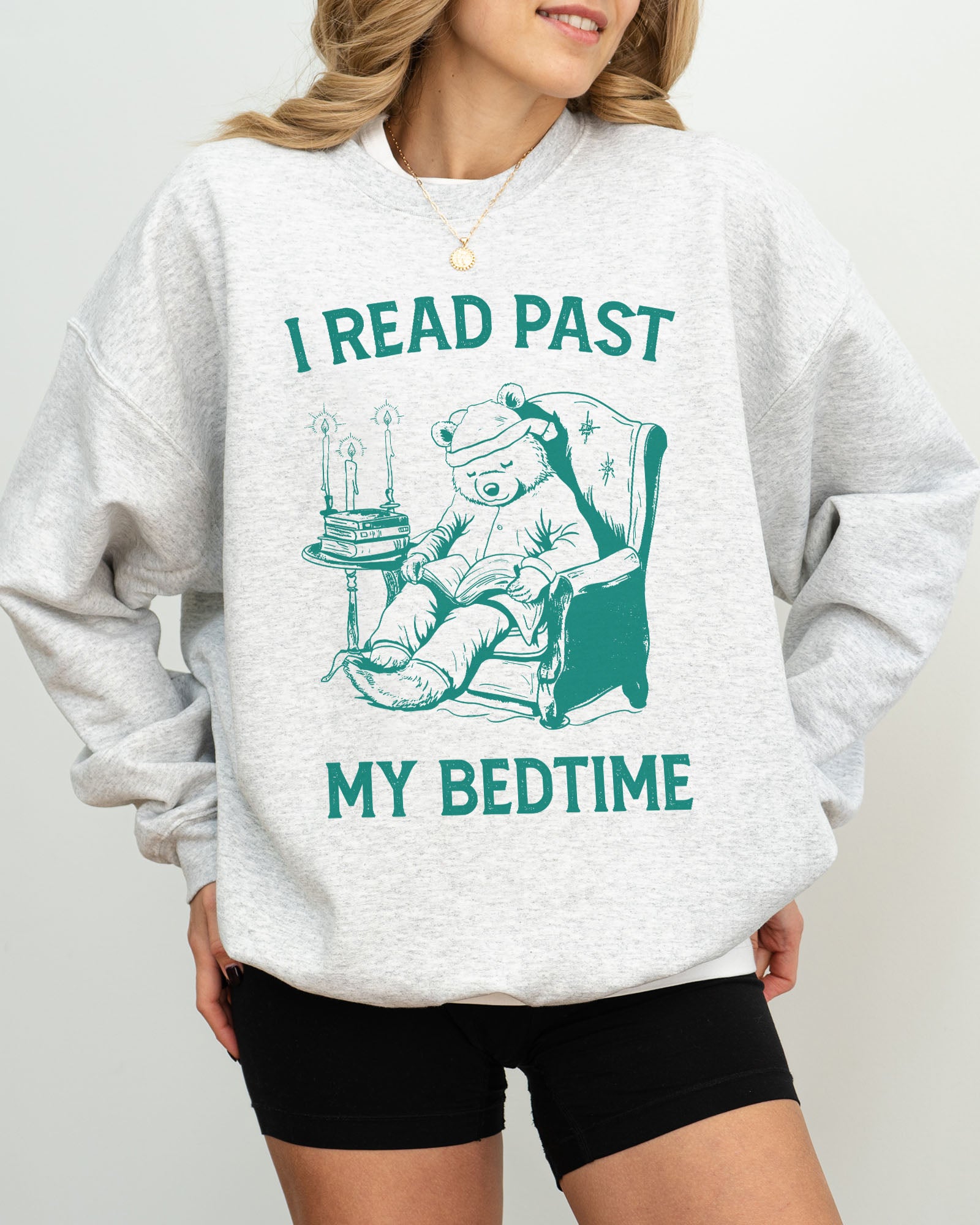 Model wearing ash color sweatshirt with 'I Read Past my Bedtime' graphic design