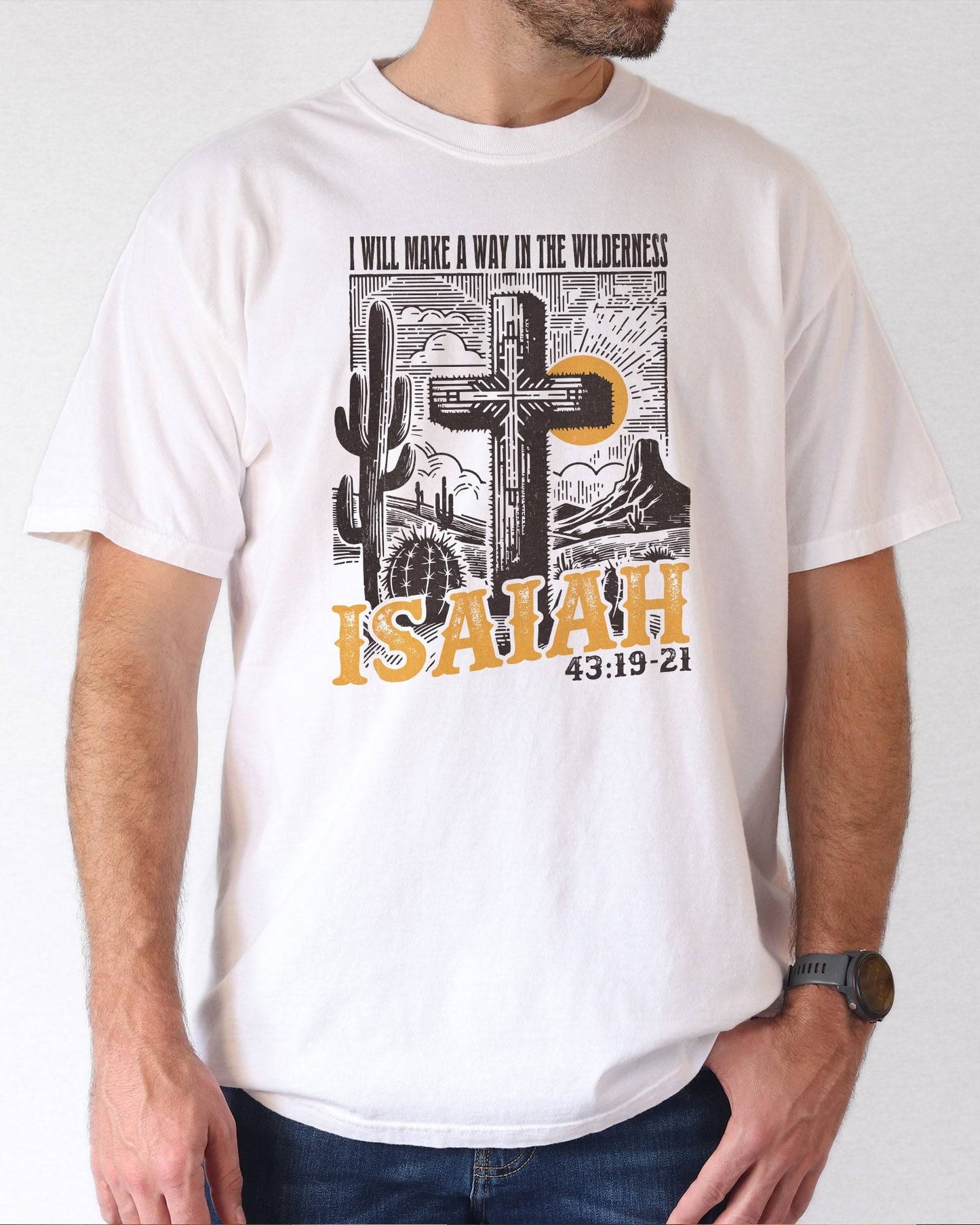Man wearing a white 'I Will Make a Way in the Wilderness – Isaiah 43:19-21' shirt with a retro graphic of a western desert and a Christian cross.