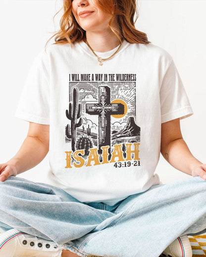 Woman wearing a white 'I Will Make a Way in the Wilderness – Isaiah 43:19-21' shirt with a retro graphic of a western desert and a Christian cross.