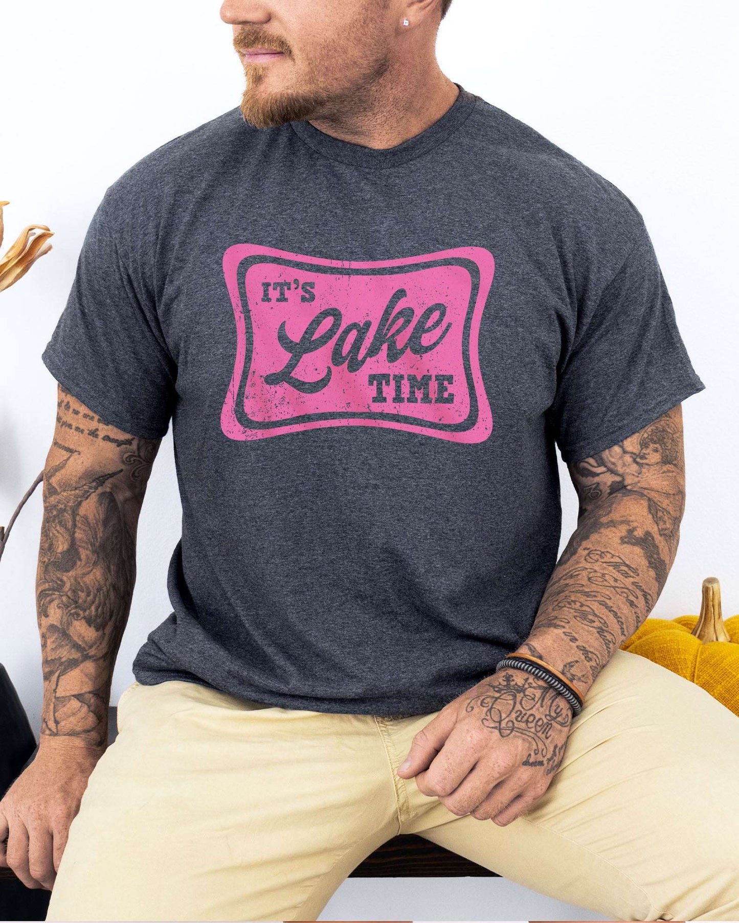 Model wearing dark heather color shirt with 'It's Lake Time' graphic design