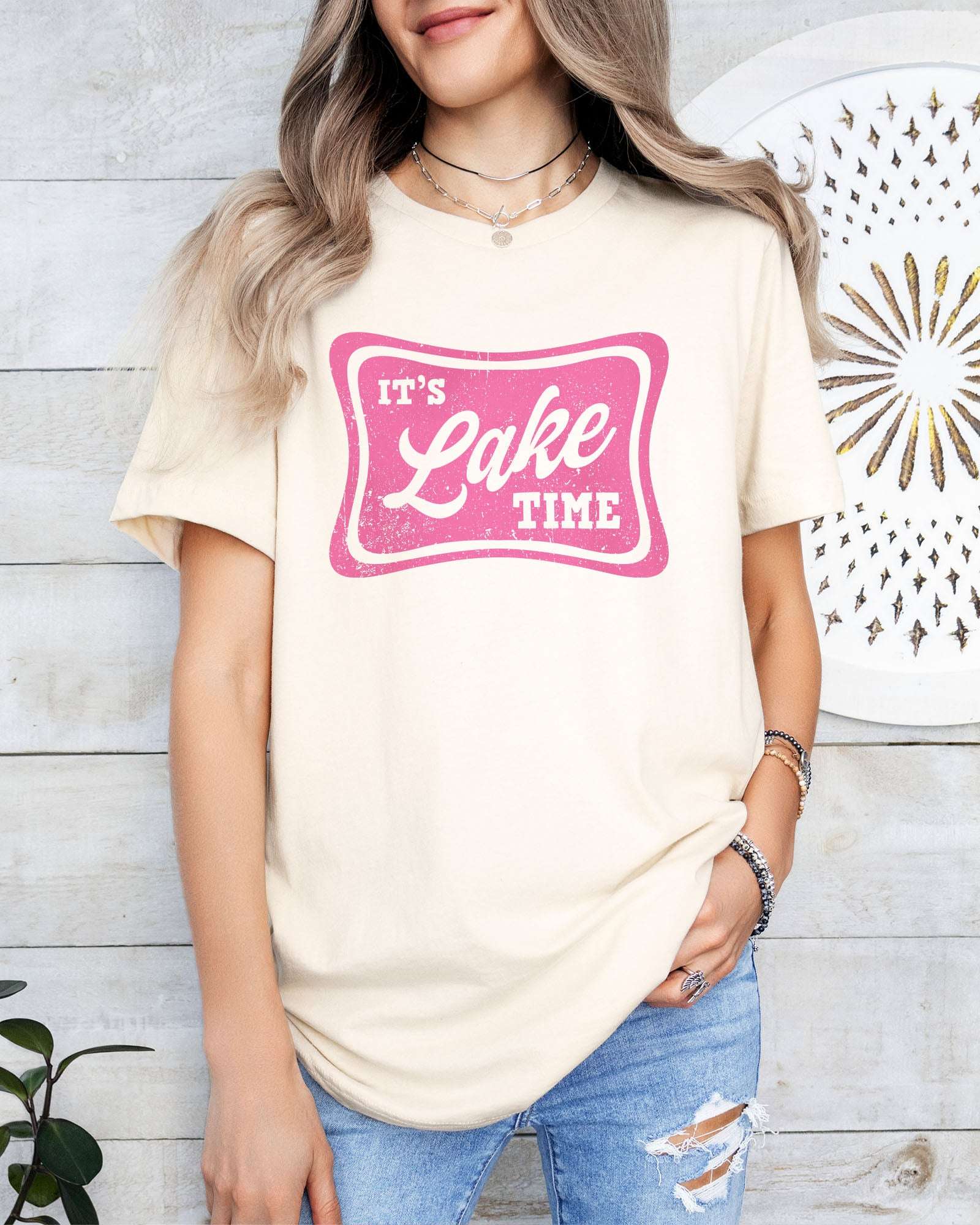 Model wearing natural color shirt with 'It's Lake Time' graphic design