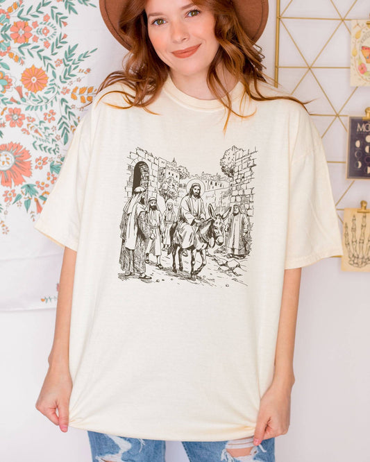 Model wearing ivory color shirt with Jesus Riding Donkey christian graphic design
