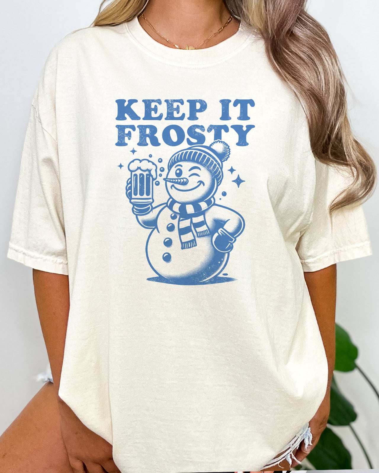 Woman wearing a natural beige retro snowman graphic tee with the quote Keep It Frosty