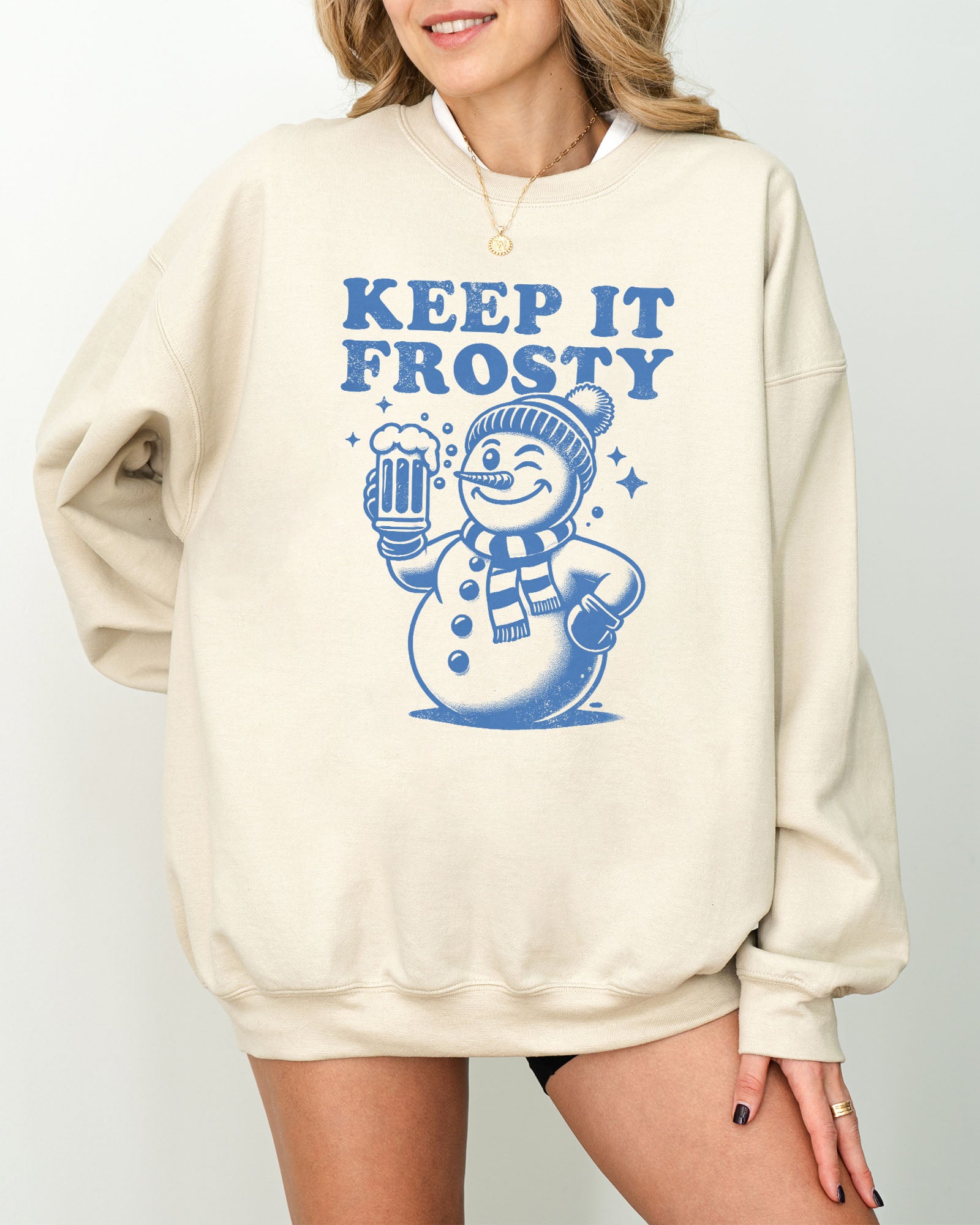 Model wearing sand color sweatshirt with 'Keep It Frosty' snowman graphic design
