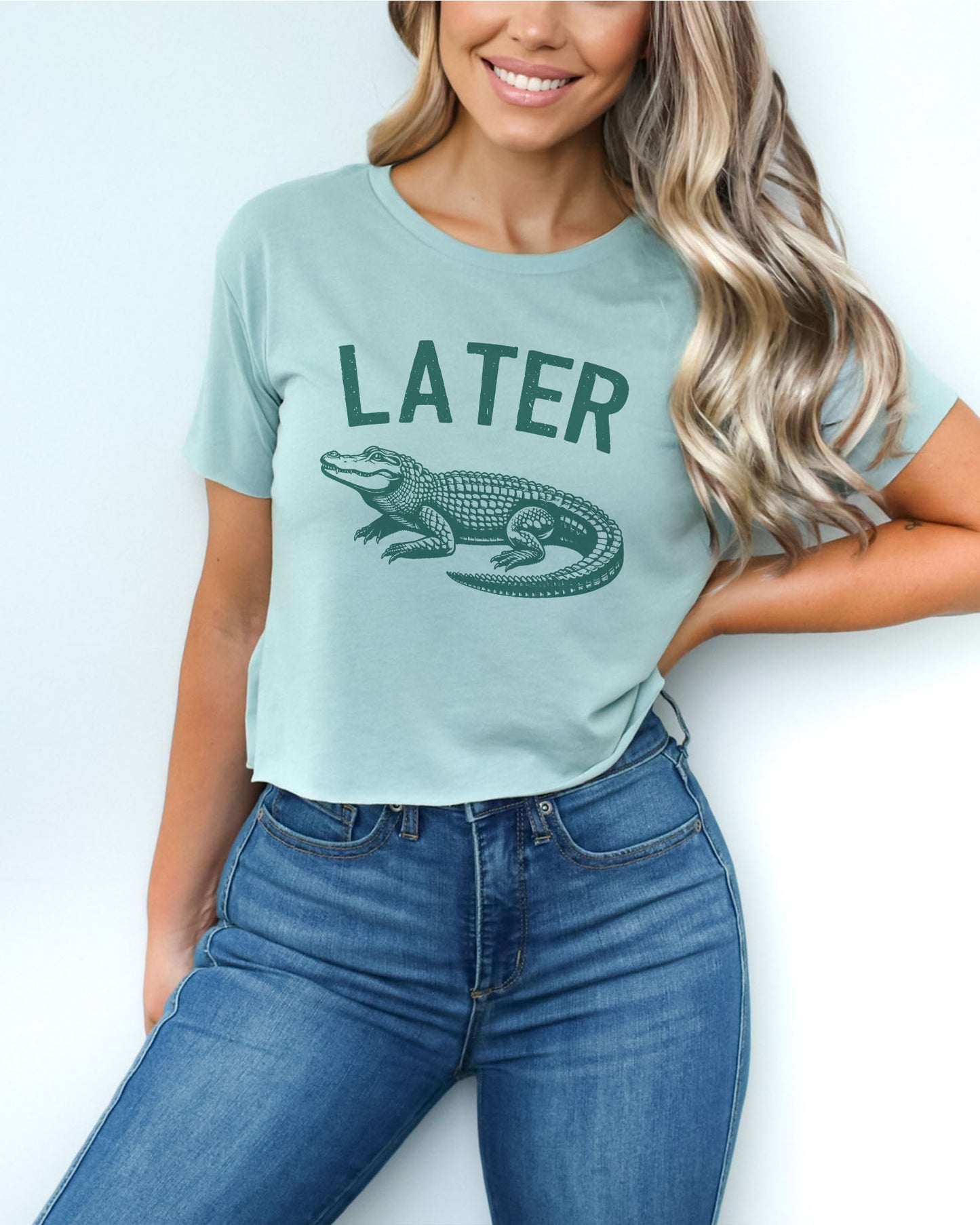 Woman wearing a stonewash-green-colored 'Later Gator' crop top featuring a funny retro alligator graphic.