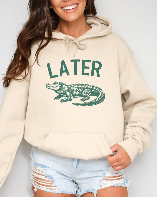 Woman wearing a sand beige colored 'Later Gator' hoodie featuring a funny retro alligator graphic.