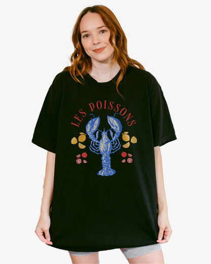 Woman wearing a black 'Les Poissons' shirt with a retro graphic of a lobster.