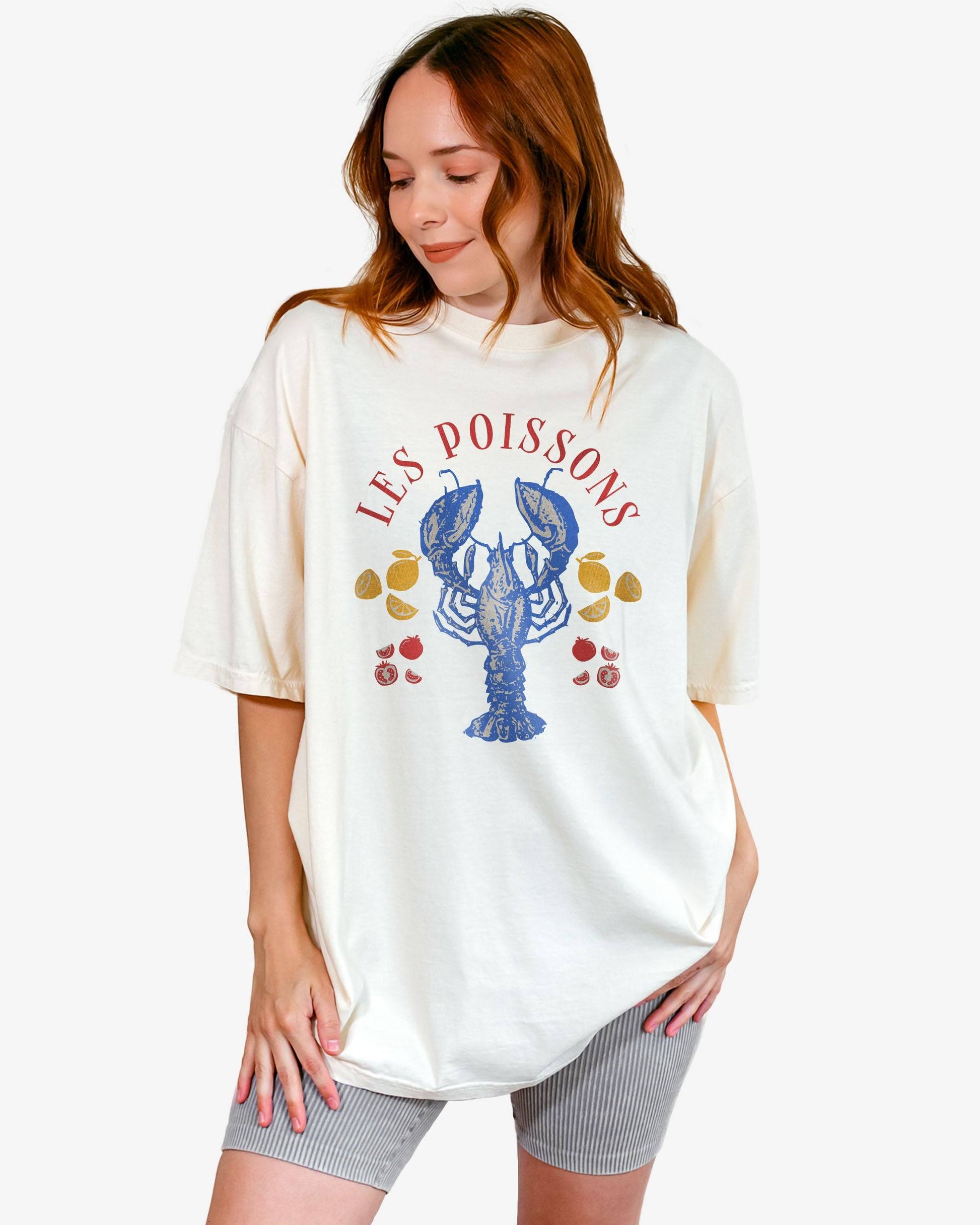 Woman wearing an ivory 'Les Poissons' shirt with a retro graphic of a lobster.