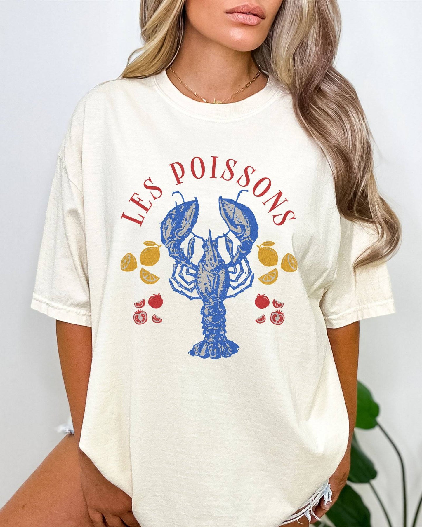 Woman wearing an ivory-colored 'Les Poissons' shirt with a retro graphic of a lobster.