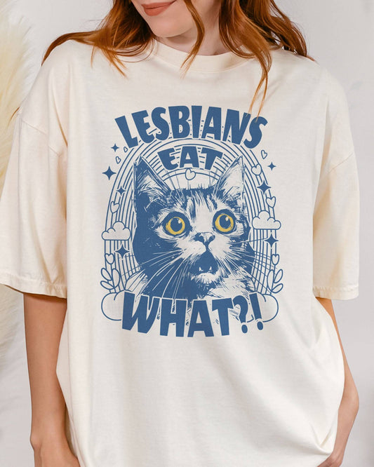 Close-up of woman wearing "Lesbians Eat What?!" shirt in ivory color with a funny retro graphic of a shocked cat.