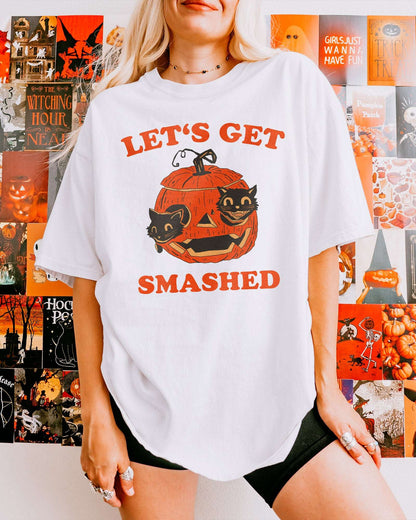 Woman wearing Let’s Get Smashed shirt in white retro Halloween graphic of two black cats inside a carved pumpkin