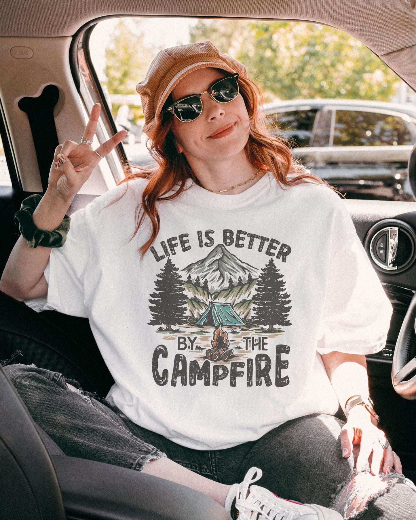 Woman wearing 'Life Is Better By The Campfire' shirt in white color and with  retro camping nature graphic