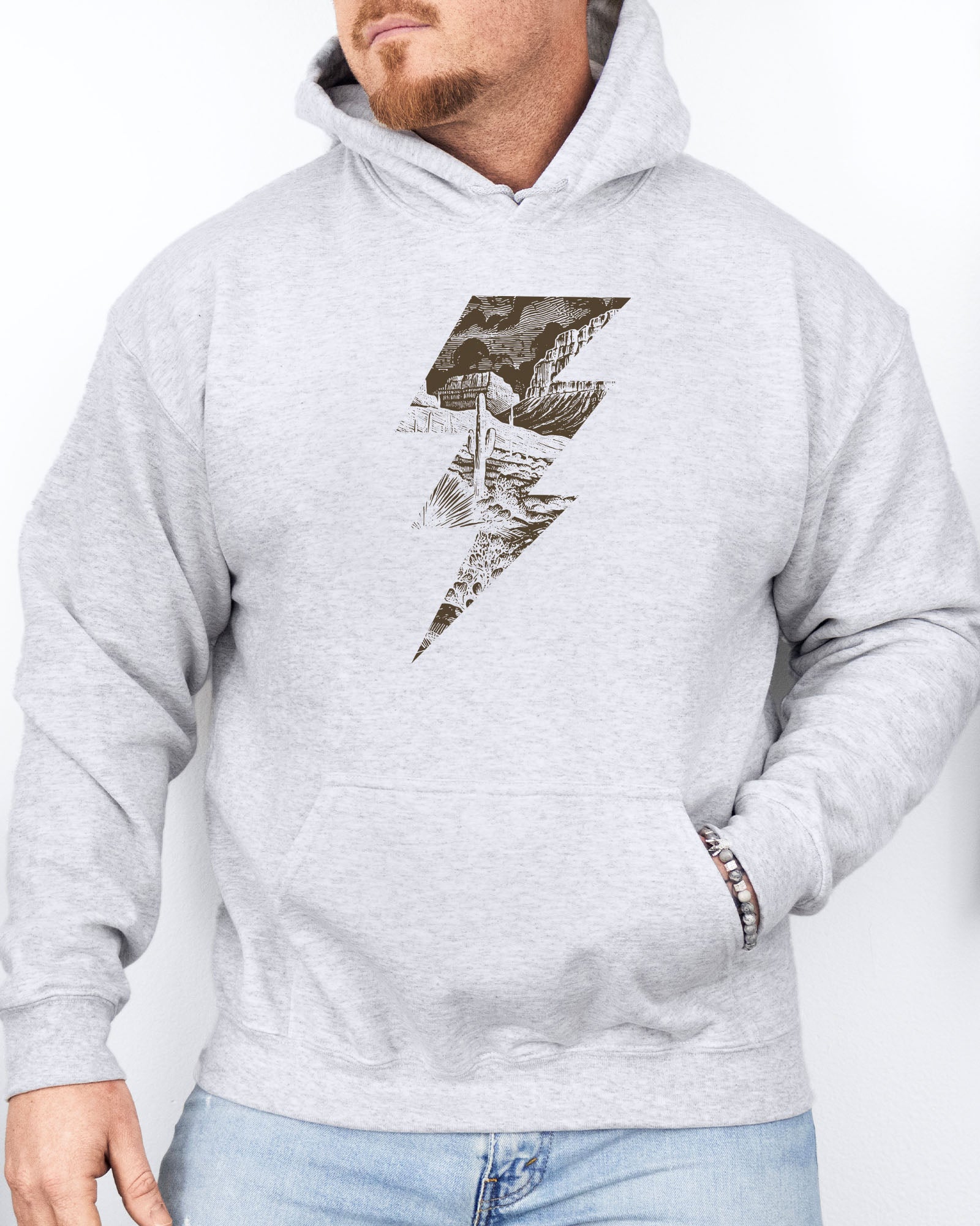 Man wearing an ash gray hoodie featuring a retro vintage-style western desert scenery lightning bolt graphic.