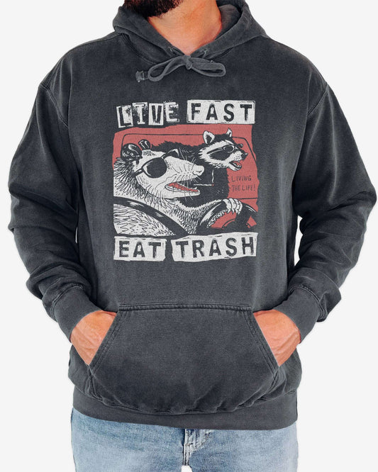 Man wearing pepper 'Live Fast Eat Trash' hoodie with a funny retro graphic of two raccoons driving a car.