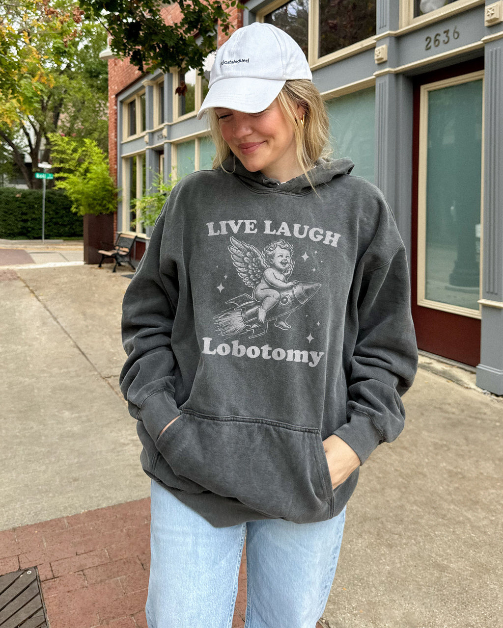 Woman wearing pepper 'Live Laugh Lobotomy' hoodies with funny retro graphic of armor flying on a rocket.
