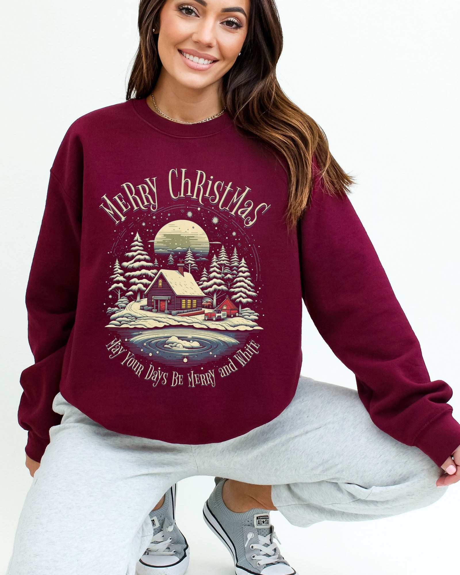 Model wearing maroon color sweatshirt with 'May Your Days Be Merry And Bright' Christmas graphic design